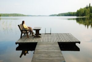 Symbolbild: Eine Frau sitzt am Wasser und entspannt sich